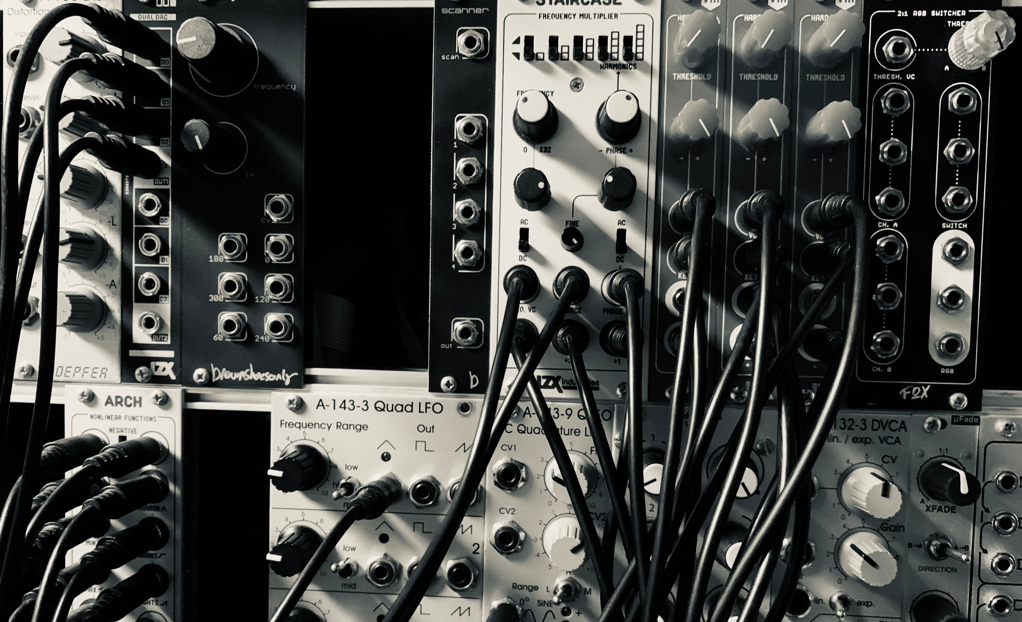 A modular synthesizer with lots of patch cables connected to it.